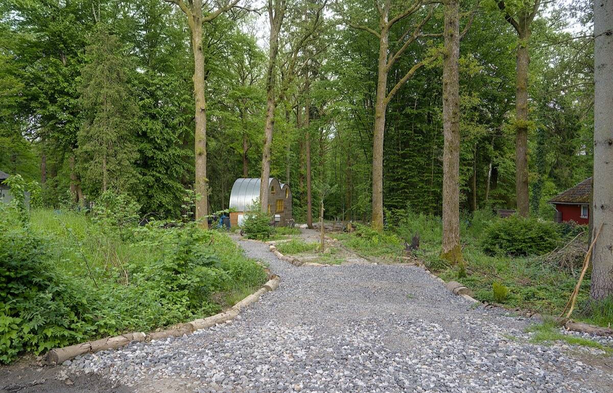 Een nieuw grindpad tussen de bomen naar een klein huis